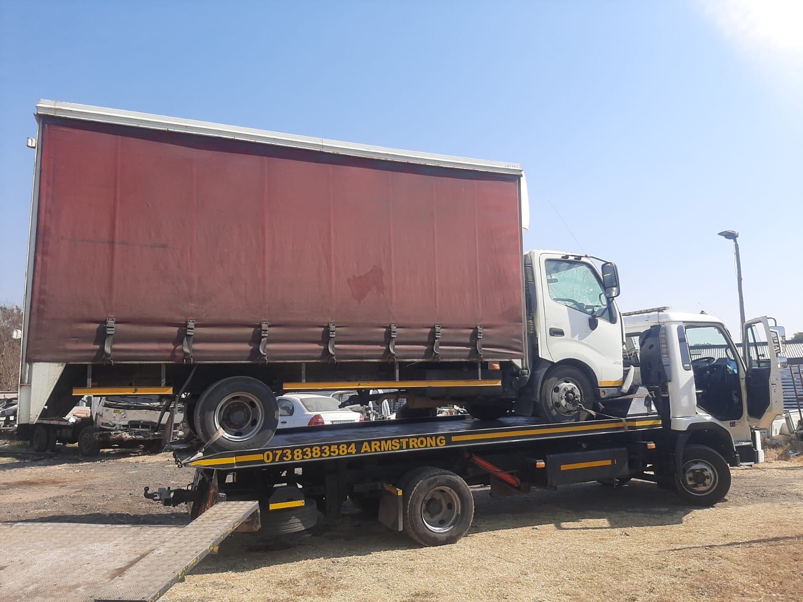Curtain-side delivery truck loaded on the Armstrong Towing rollback
