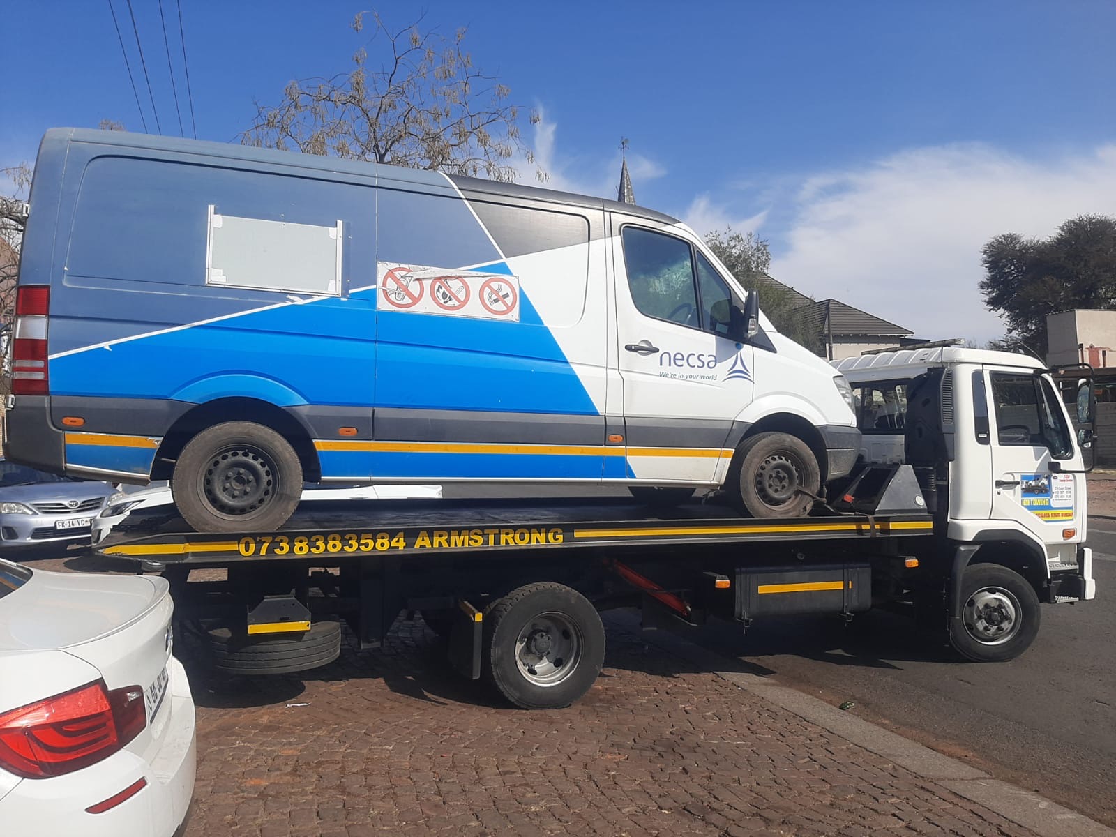 Branded Mercedes Sprinter van on the Armstrong Towing flatbed